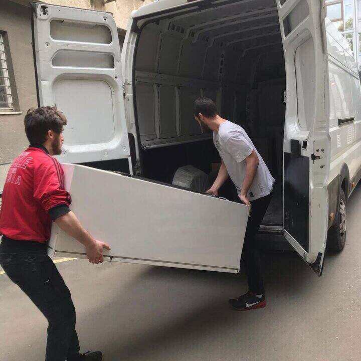 Dva radnika utovaruju frižider u kombi vozilo